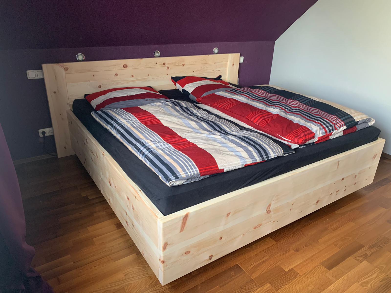 Doppelbett aus Zirbenholz mit bunter Bettwäsche