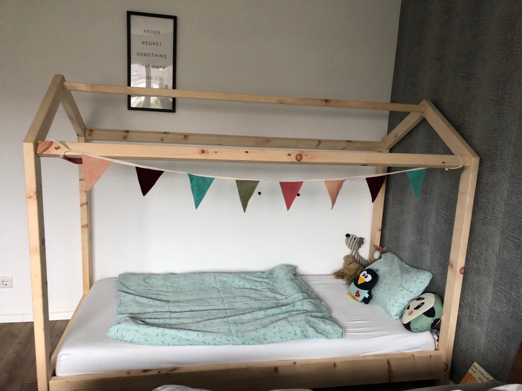 Kinderbett aus Zirbenholz mit Fähnchen, blauer Bettwäsche und Kuscheltierebn